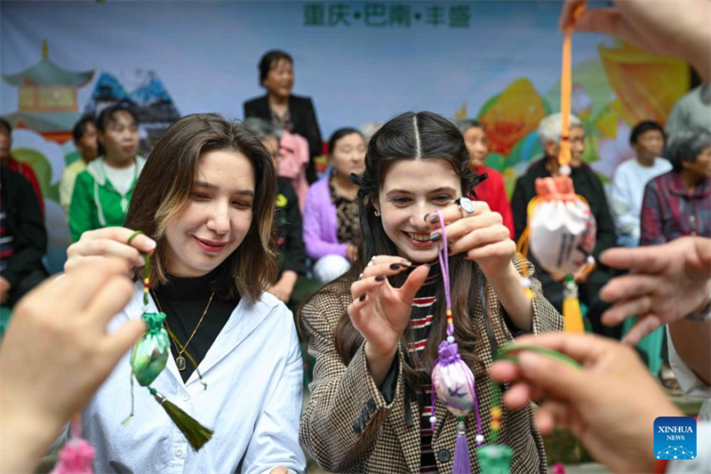 Οι κάτοικοι της περιοχής και οι διεθνείς φοιτητές προσπαθούν να φτιάξουν φακελάκια στην αρχαία πόλη Φενγκσένγκ της περιοχής Μπανάν στον Δήμο Τσονγκκίνγκ, στις 28 Μαΐου του 2025. (Φωτογραφία / Xinhua)