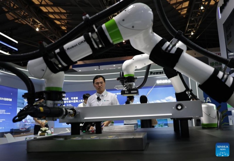 Υπάλληλος παρακολουθεί συνεργατικά ρομπότ να επιδεικνύουν τη συναρμολόγηση μπαταριών και τον έλεγχο καλωδιώσεων κατά τη διάρκεια της 11ης Διεθνούς Έκθεσης Τεχνολογίας της Κίνας (Σαγκάη), στη Σαγκάη, στις 11 Ιουνίου του 2025.