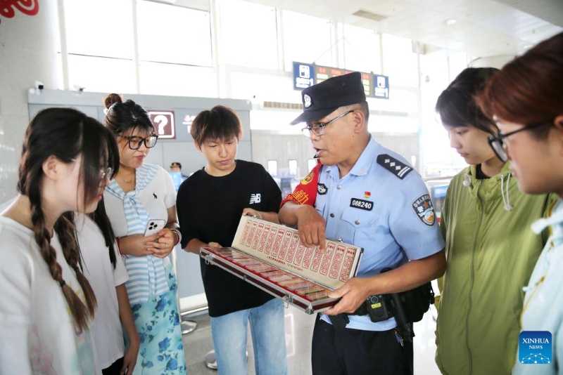Aστυνομικός παρουσιάζει γνώσεις για την καταπολέμηση των ναρκωτικών σε επιβάτες σε σιδηροδρομικό σταθμό στην πόλη Λιανγιουνγκάνγκ, της επαρχίας Τζιανγκσού, στις 25 Ιουνίου του 2025. (Φωτογραφία / Xinhua)