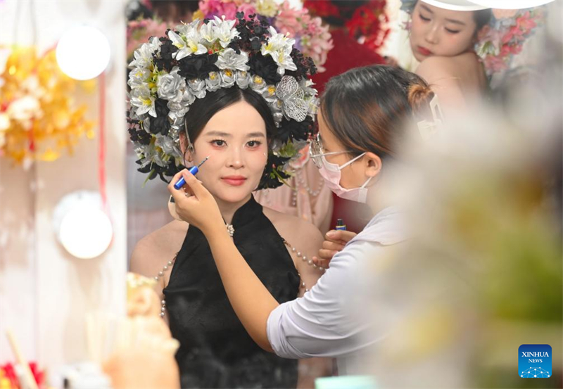 Τουρίστρια που φοράει ένα λουλουδάτο στεφάνι κεφαλιού κάνει το μακιγιάζ της σε ένα στούντιο ταξιδιωτικής φωτογραφίας στο χωριό Σουνπού, στην πόλη Τσουαντζόου της επαρχίας Φουτζιάν, στις 18 Αυγούστου του 2025. (Φωτογραφία / Xinhua)