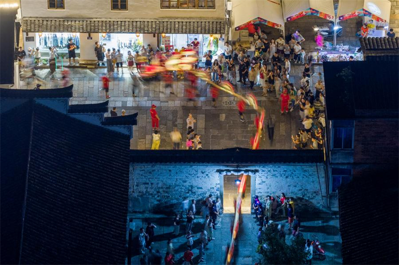 Αεροφωτογραφία που τραβήχτηκε στις 5 Οκτωβρίου του 2025 δείχνει ανθρώπους να παρακολουθούν μια παράσταση του χορού του δράκου από ξύλινο πάγκο στην κομητεία Πουτζιάνγκ της επαρχίας Τζετζιάνγκ. (Φωτογραφία / Xinhua)