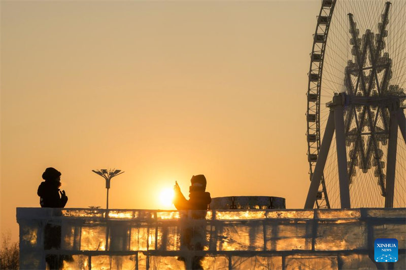 Οι τουρίστες διασκεδάζουν στο ηλιοβασίλεμα στον Κόσμο Πάγου και Χιονιού της πόλης Χαρμπίν